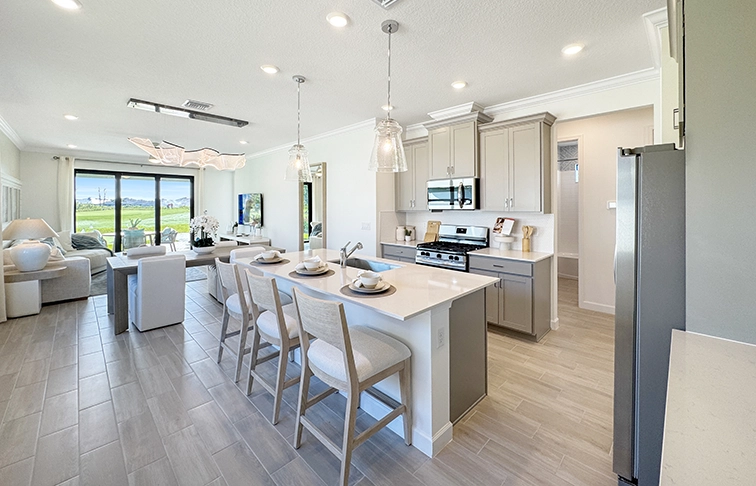 Open kitchen with gray cabinets, island seating, and adjacent living room.