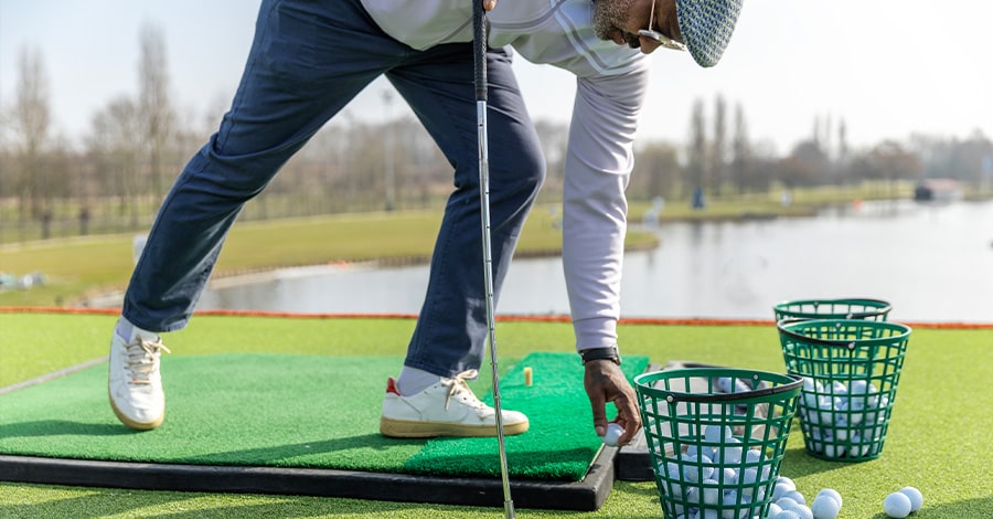 Man setting up golf shot style=