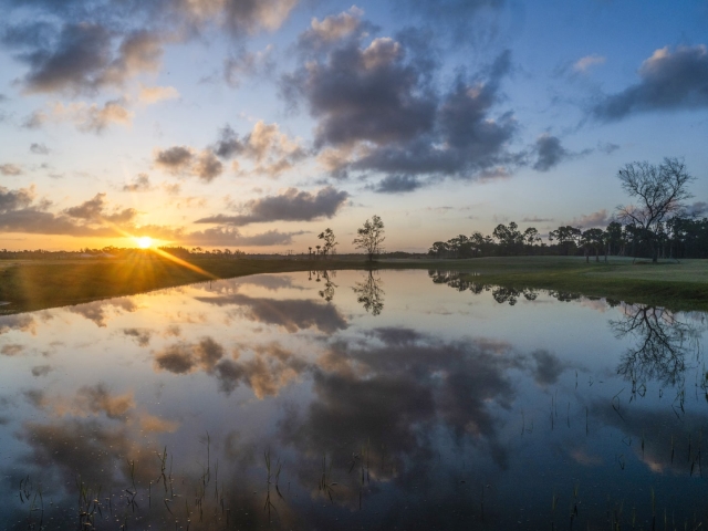 sun over the water on golf course