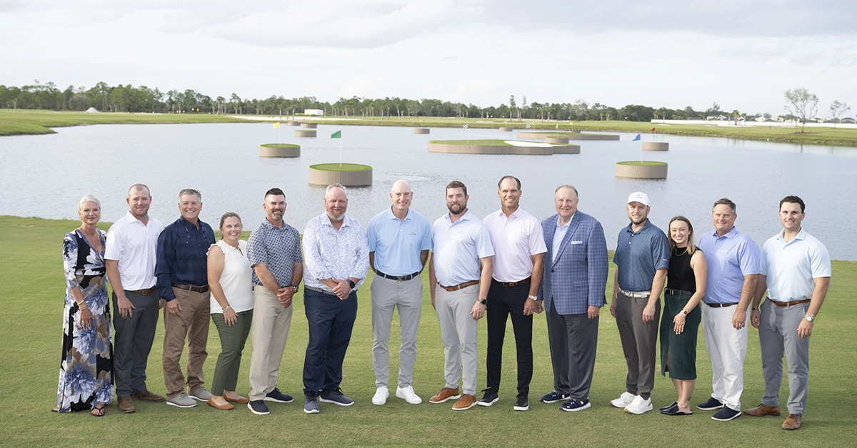 Group of people standing together on the golf course near floating greens.