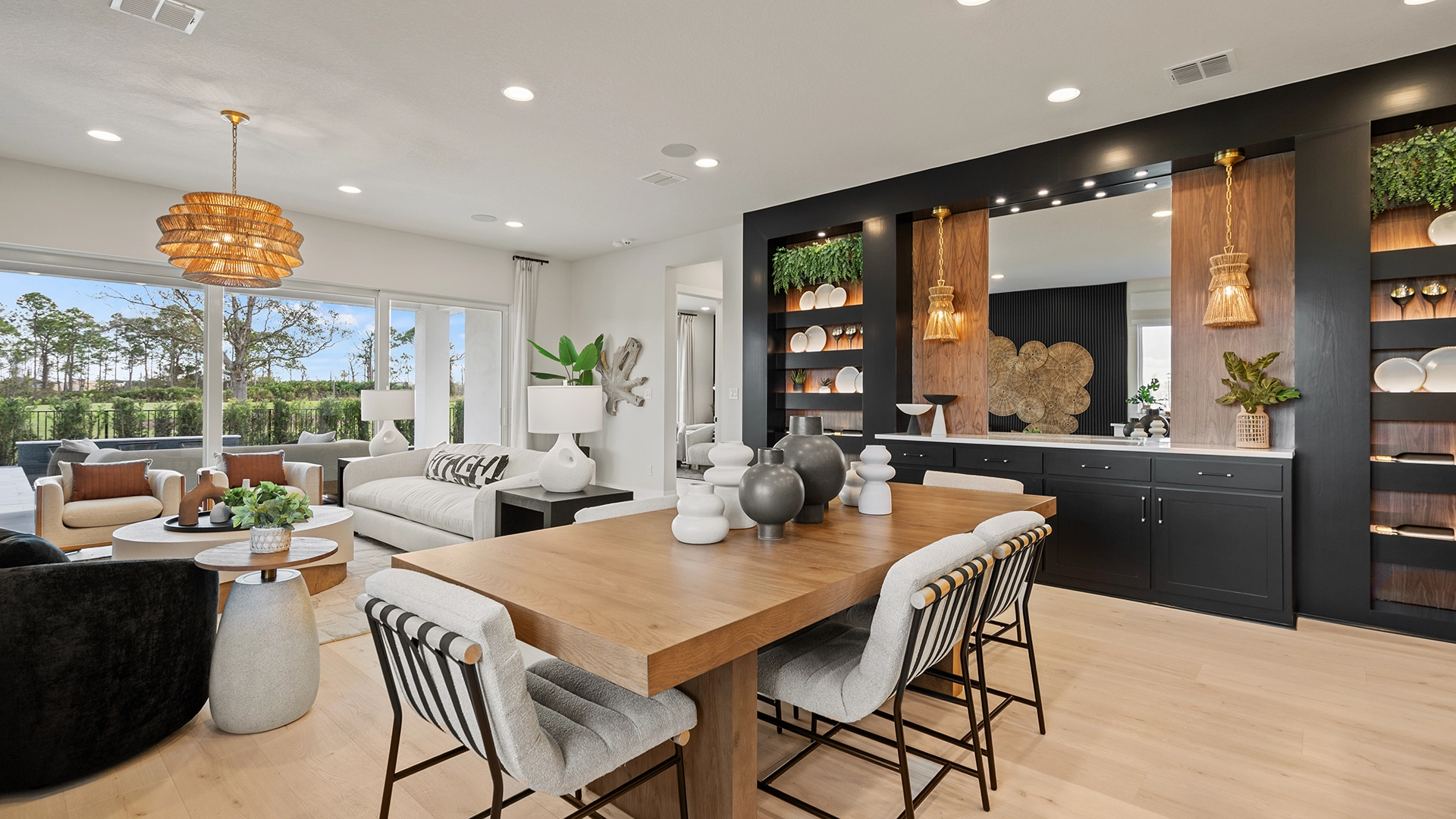 Modern open-concept dining and living room with wood table, sofas, and large windows.
