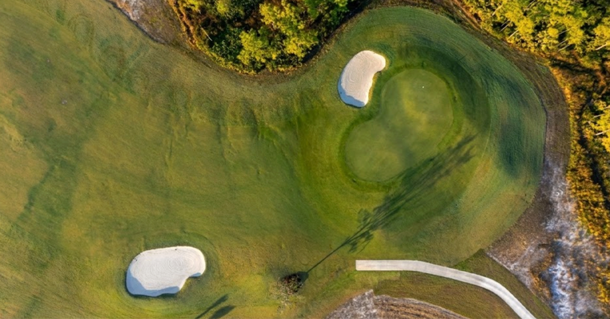 Aerial view of golf green with sand bunkers and surrounding trees
