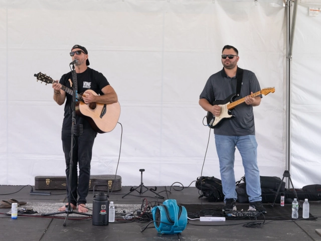 Two musicians playing guitars on stage