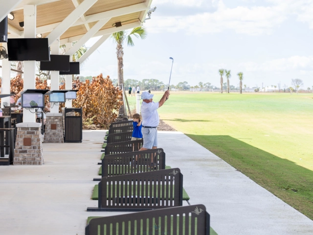 Man swinging golf club with child watching