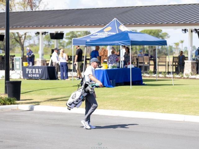 Golfer carrying bag past event tents