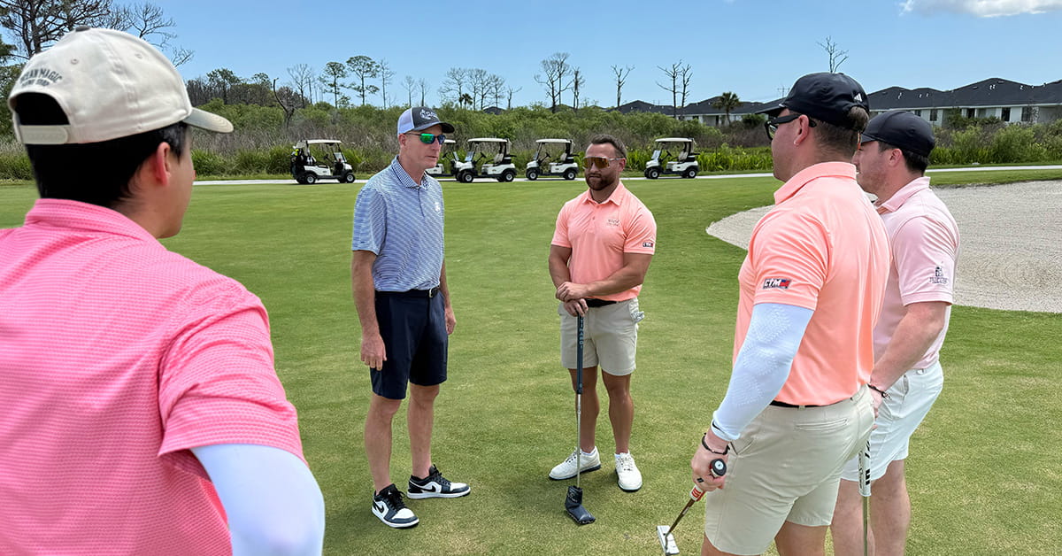 Golfers stand together on a green discussing their next shots.