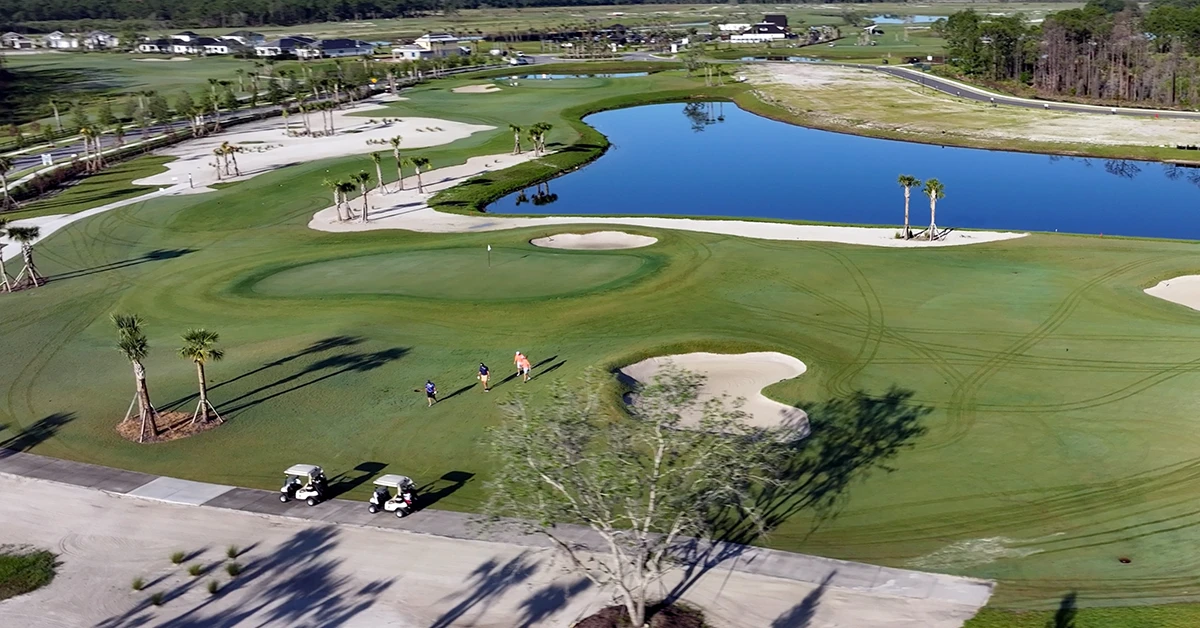 Aerial view of a golf course with greens, bunkers, and water.